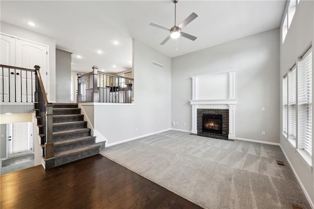 11704 N Laurel Ave, Kansas City, MO 64157 - unfurnished living room with stairway, a ceiling fan, a fireplace with flush hearth, wood finished floors, and carpet