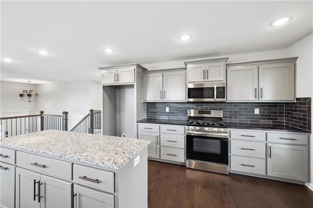 11704 N Laurel Ave, Kansas City, MO 64157 - kitchen featuring appliances with stainless steel finishes, gray cabinetry, tasteful backsplash, dark wood-type flooring, and light stone counters