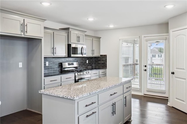 11704 N Laurel Ave, Kansas City, MO 64157 - kitchen featuring stainless steel appliances, dark wood-style flooring, backsplash, light stone countertops, and a center island