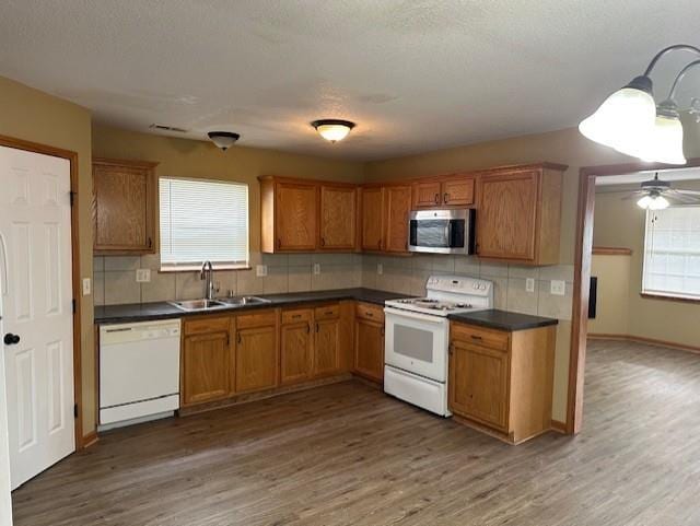 1002 NE Deer Creek Rd, Grain Valley, MO 64029 - kitchen with white appliances, wood finished floors, decorative backsplash, and dark countertops