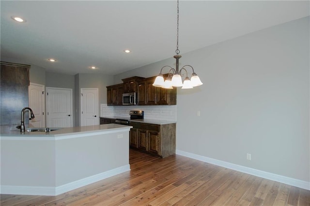 3718 NE 90th Ter, Kansas City, MO 64156 - kitchen with electric stove, stainless steel microwave, backsplash, a chandelier, and light wood finished floors