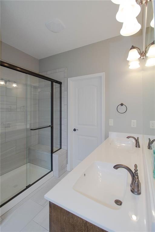 3718 NE 90th Ter, Kansas City, MO 64156 - bathroom featuring a stall shower, double vanity, a chandelier, and tile patterned floors