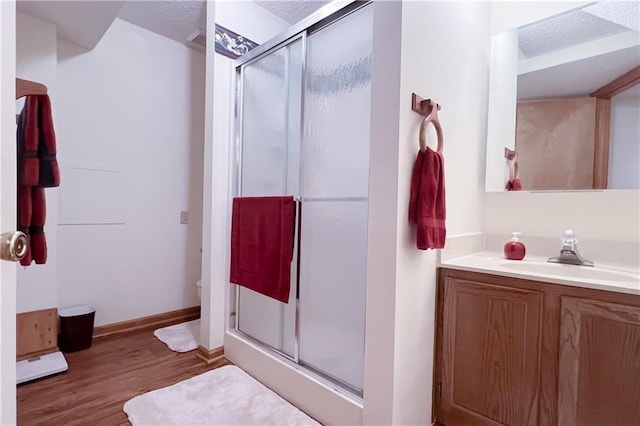 413 Quail Trl, Warrensburg, MO 64093 - bathroom featuring wood finished floors, a shower stall, vanity, and a textured ceiling