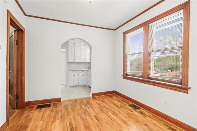 414 Dickinson Rd, Independence, MO 64050 - unfurnished room featuring ornamental molding, light wood-style flooring, and arched walkways
