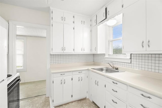 414 Dickinson Rd, Independence, MO 64050 - kitchen featuring electric range, plenty of natural light, white cabinets, and backsplash