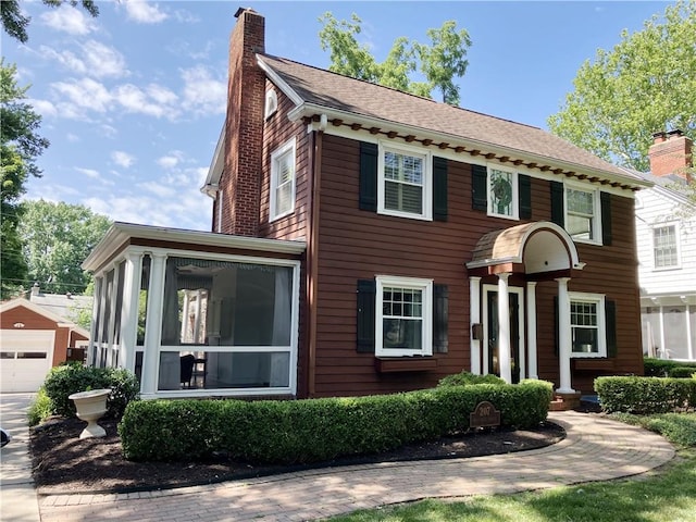 207 W 66th St, Kansas City, MO 64113 - colonial-style house with a chimney, a sunroom, a garage, an outbuilding, and driveway