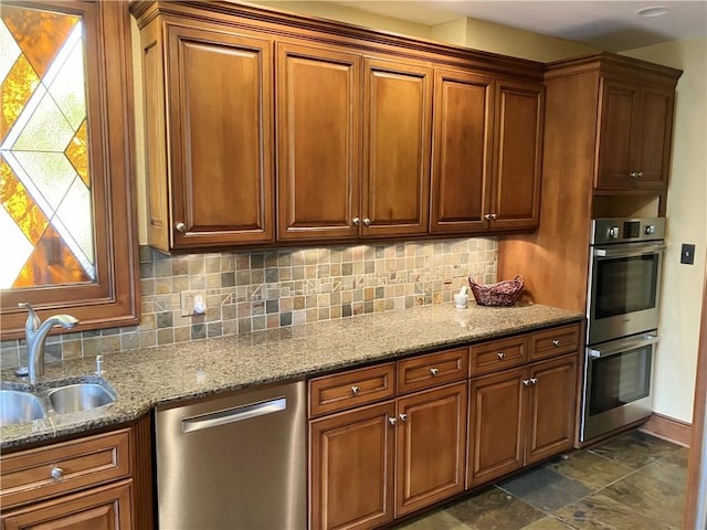207 W 66th St, Kansas City, MO 64113 - kitchen featuring stainless steel appliances, backsplash, light stone countertops, and brown cabinetry