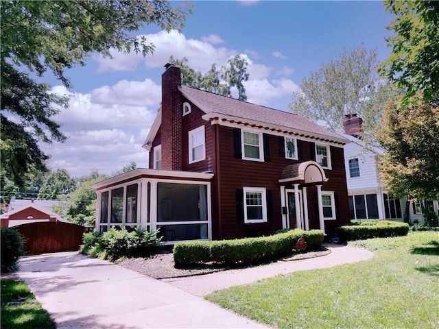 207 W 66th St, Kansas City, MO 64113 - colonial house featuring a sunroom, a chimney, and a front lawn
