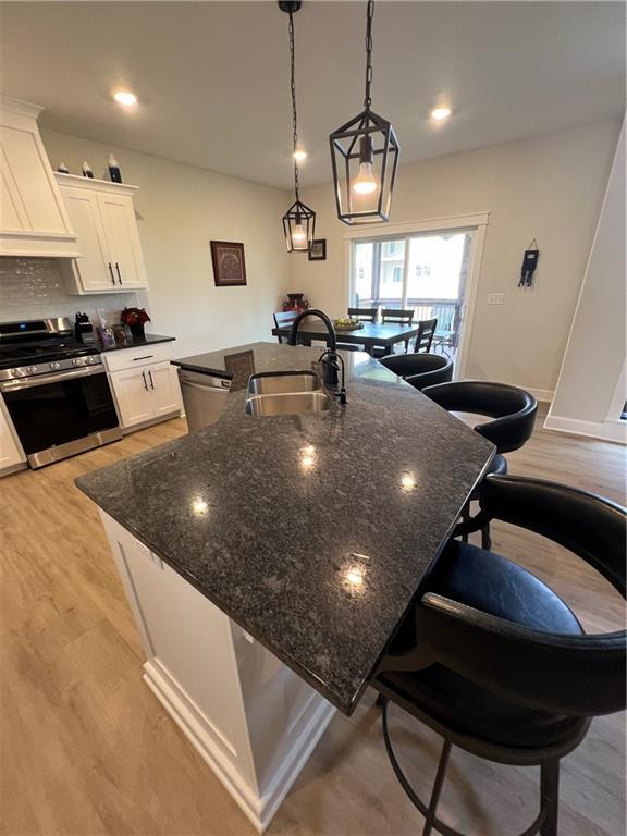 2321 Dovecott Dr, Kearney, MO 64060 - kitchen featuring appliances with stainless steel finishes, custom exhaust hood, a spacious island, a breakfast bar area, and white cabinets
