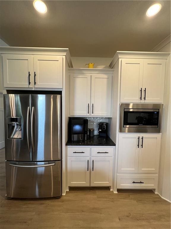 2321 Dovecott Dr, Kearney, MO 64060 - kitchen with appliances with stainless steel finishes, white cabinetry, light wood finished floors, dark countertops, and recessed lighting