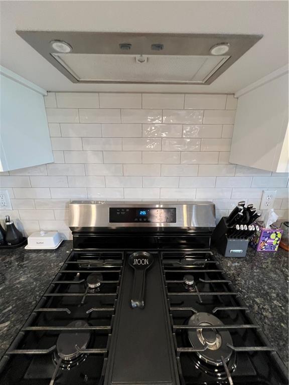 2321 Dovecott Dr, Kearney, MO 64060 - kitchen view of stainless steel gas range, tasteful backsplash, exhaust hood, ornamental molding, and dark stone countertops