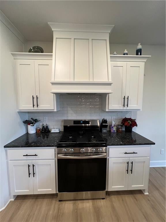 2321 Dovecott Dr, Kearney, MO 64060 - kitchen with gas range, light wood-style flooring, premium range hood, white cabinets, and backsplash