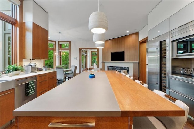 2720 Verona Cir, Mission Hills, KS 66208 - kitchen featuring dishwasher, brown cabinets, light countertops, a spacious island, and pendant lighting