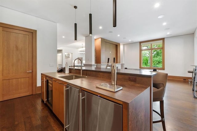 2720 Verona Cir, Mission Hills, KS 66208 - kitchen featuring dark wood-style flooring, a center island with sink, brown cabinets, pendant lighting, and recessed lighting