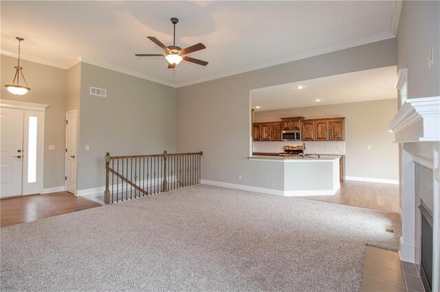 8911 N Monroe Ave, Kansas City, MO 64156 - entrance foyer featuring carpet floors, a fireplace with flush hearth, a ceiling fan, and crown molding