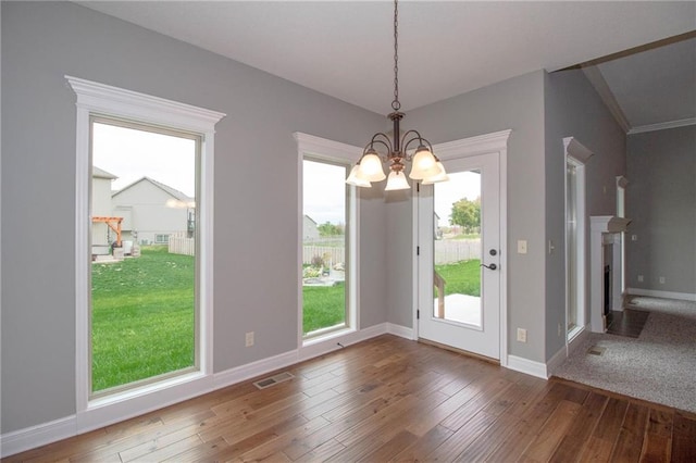 8911 N Monroe Ave, Kansas City, MO 64156 - unfurnished dining area featuring a chandelier, wood-type flooring, healthy amount of natural light, and a fireplace with flush hearth