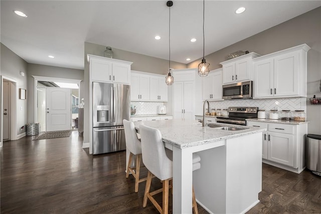 14168 Nicollete Ct, Basehor, KS 66007 - kitchen with appliances with stainless steel finishes, white cabinetry, decorative backsplash, dark wood-type flooring, and an island with sink