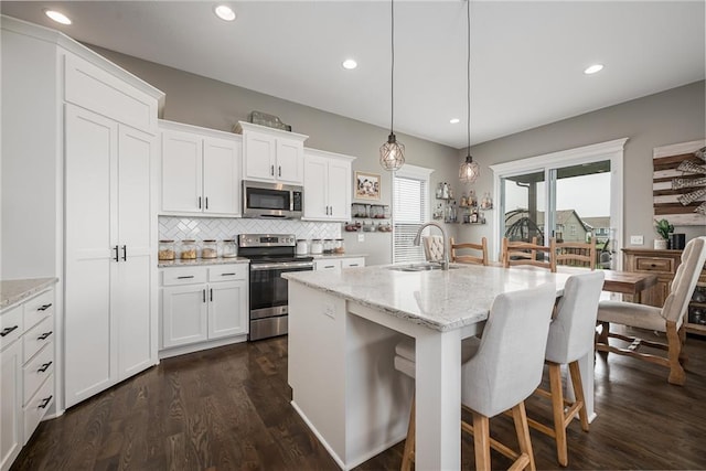 14168 Nicollete Ct, Basehor, KS 66007 - kitchen with stainless steel appliances, backsplash, white cabinets, light stone counters, and recessed lighting