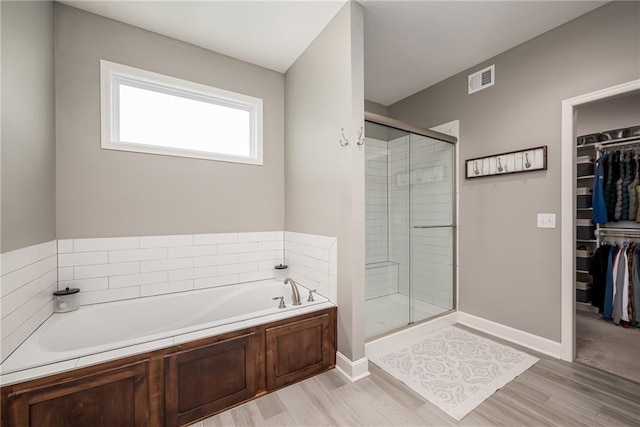 14168 Nicollete Ct, Basehor, KS 66007 - full bath featuring a stall shower, a bath, a walk in closet, and wood finished floors