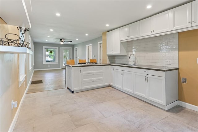 3640 Cleveland Ave, Kansas City, MO 64128 - kitchen with white cabinets, dark countertops, tasteful backsplash, recessed lighting, and ceiling fan