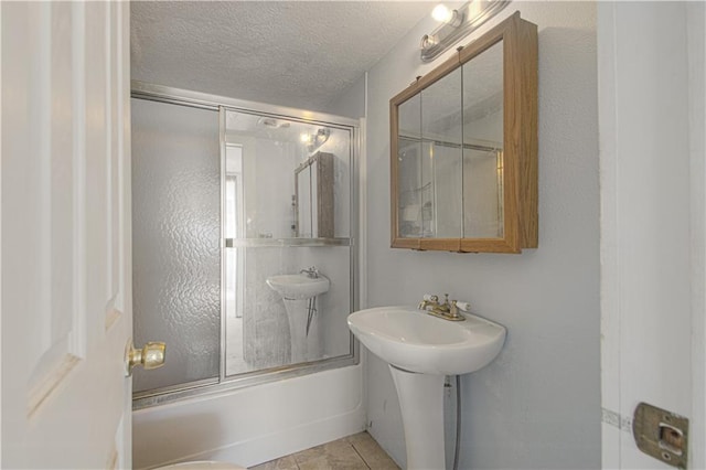 924 N Park Ave, Independence, MO 64050 - bathroom featuring bath / shower combo with glass door, a textured ceiling, and tile patterned flooring