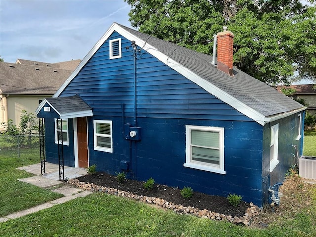7104 N Cherry St, Gladstone, MO 64118 - back of house with a shingled roof, a chimney, and concrete block siding