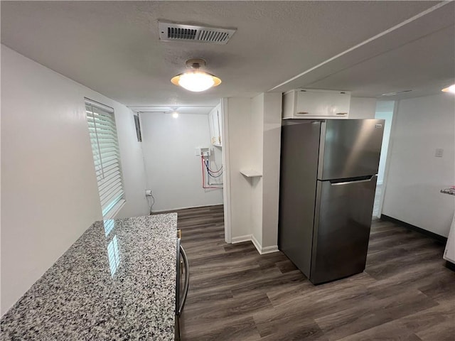 7104 N Cherry St, Gladstone, MO 64118 - kitchen featuring freestanding refrigerator, white cabinets, dark wood-style floors, light stone countertops, and a textured ceiling