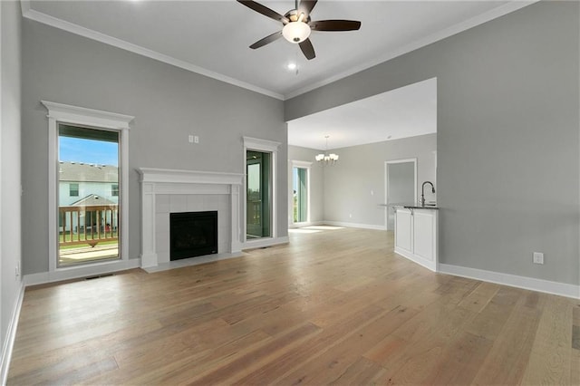 3707 NE 90th St, Kansas City, MO 64156 - unfurnished living room featuring a ceiling fan, light wood-type flooring, crown molding, a chandelier, and a fireplace