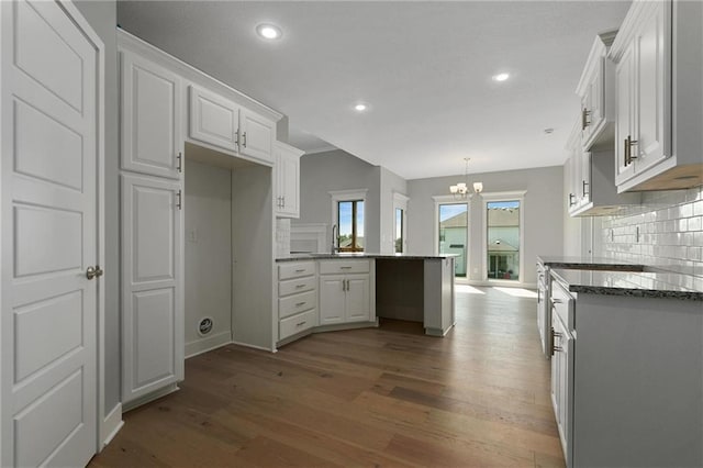 3707 NE 90th St, Kansas City, MO 64156 - kitchen featuring a chandelier, wood finished floors, decorative backsplash, a peninsula, and white cabinetry