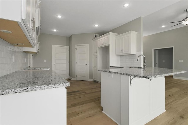3707 NE 90th St, Kansas City, MO 64156 - kitchen featuring a peninsula, backsplash, light stone countertops, light wood-type flooring, and ceiling fan