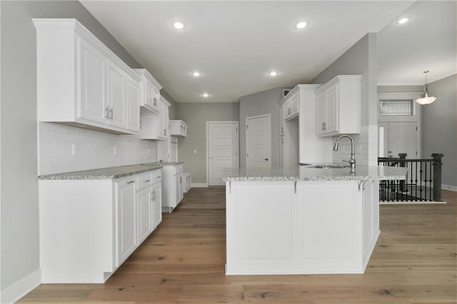 3707 NE 90th St, Kansas City, MO 64156 - kitchen featuring a peninsula, light stone counters, decorative backsplash, light wood-style flooring, and white cabinets
