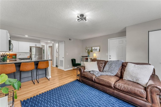 1509 W 25th Ct Unit A2, Lawrence, KS 66046 - living room featuring light wood-style floors and a textured ceiling