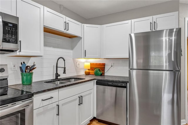 1509 W 25th Ct Unit A2, Lawrence, KS 66046 - kitchen with appliances with stainless steel finishes, white cabinetry, dark stone counters, and decorative backsplash