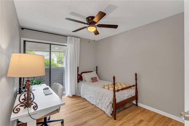 1509 W 25th Ct Unit A2, Lawrence, KS 66046 - bedroom featuring light wood finished floors, access to exterior, a textured ceiling, a ceiling fan, and an office area