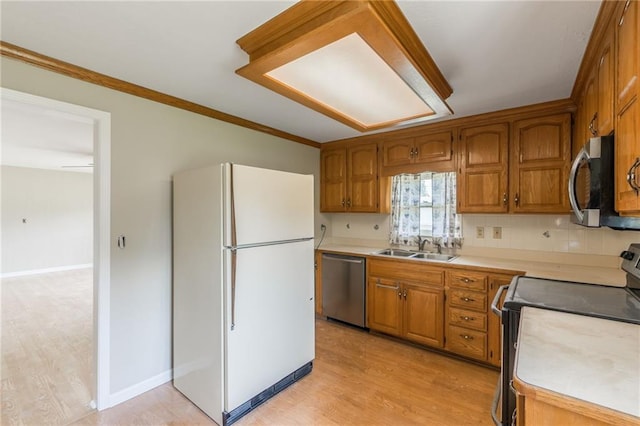 7306 N Holmes Ave, Gladstone, MO 64118 - kitchen featuring appliances with stainless steel finishes, brown cabinetry, light countertops, light wood-type flooring, and crown molding