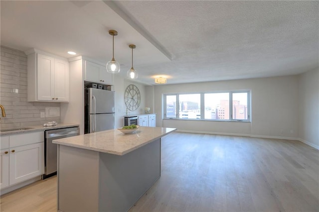 4545 Wornall Rd Unit 1009, Kansas City, MO 64111 - kitchen featuring stainless steel appliances, light wood-style floors, white cabinets, light stone countertops, and a center island