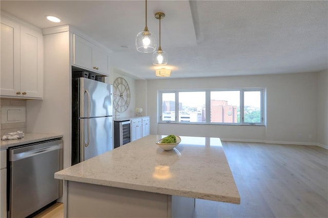 4545 Wornall Rd Unit 1009, Kansas City, MO 64111 - kitchen featuring stainless steel appliances, beverage cooler, light wood-type flooring, white cabinets, and light stone counters