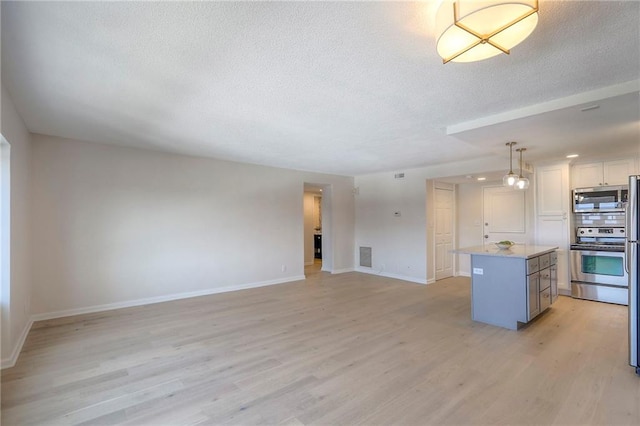 4545 Wornall Rd Unit 1009, Kansas City, MO 64111 - kitchen with appliances with stainless steel finishes, a textured ceiling, a center island, light wood finished floors, and decorative light fixtures