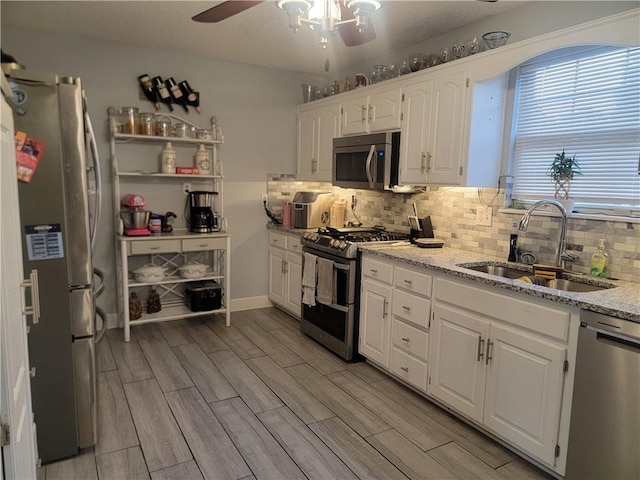 19400 E 13th St N, Independence, MO 64056 - kitchen featuring stainless steel appliances, ceiling fan, white cabinets, light stone countertops, and tasteful backsplash