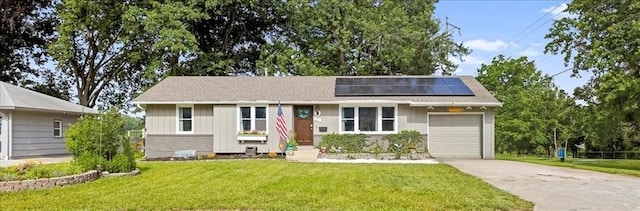 13500 Spring St, Grandview, MO 64030 - ranch-style home with board and batten siding, an attached garage, concrete driveway, roof mounted solar panels, and a front lawn