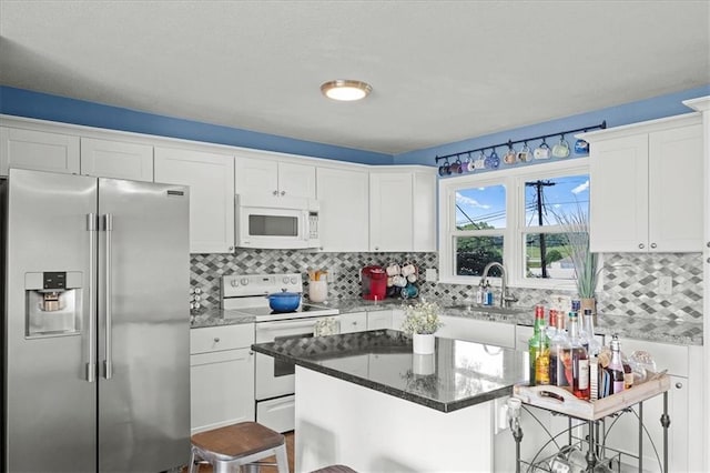 13500 Spring St, Grandview, MO 64030 - kitchen with white appliances, a kitchen bar, white cabinets, stone countertops, and a kitchen island