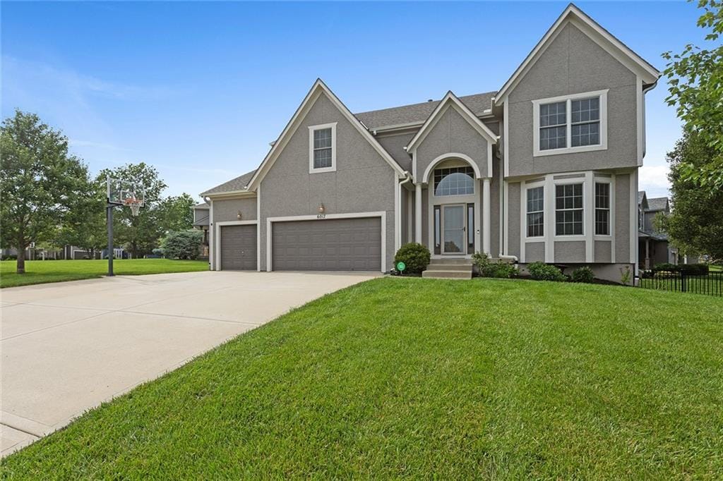 6017 Theden St, Shawnee, KS 66218 - traditional home with a garage, driveway, and stucco siding
