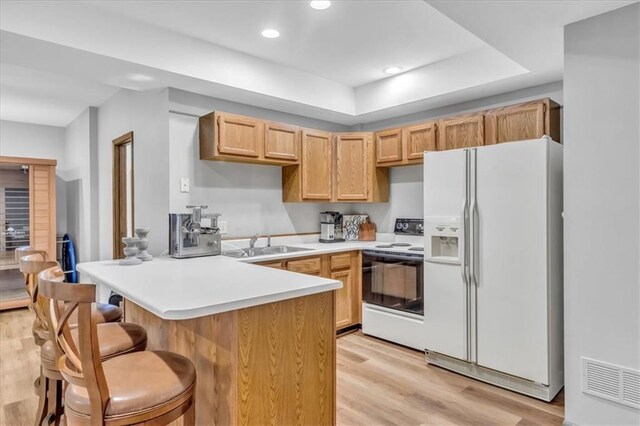 22810 SW Hampton Ct, Blue Springs, MO 64015 - kitchen featuring white appliances, a peninsula, light wood finished floors, a breakfast bar area, and recessed lighting