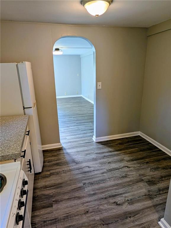 830 Locust St, Eudora, KS 66025 - kitchen featuring range, arched walkways, dark wood-style floors, freestanding refrigerator, and white cabinetry