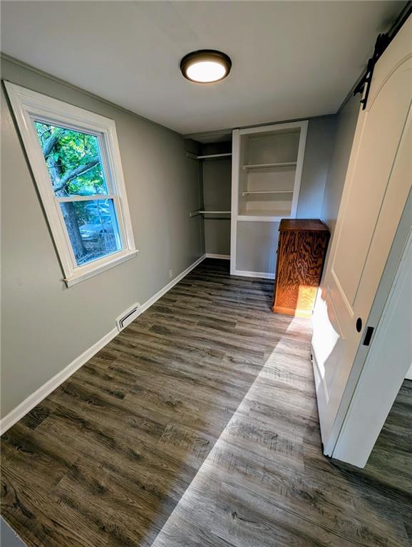 830 Locust St, Eudora, KS 66025 - unfurnished bedroom featuring a barn door and dark wood-style flooring