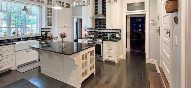 615 N Jefferson St, Carrollton, MO 64633 - kitchen with appliances with stainless steel finishes, wall chimney exhaust hood, dark countertops, decorative backsplash, and a kitchen island