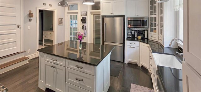 615 N Jefferson St, Carrollton, MO 64633 - kitchen with appliances with stainless steel finishes, dark wood finished floors, white cabinetry, and glass insert cabinets