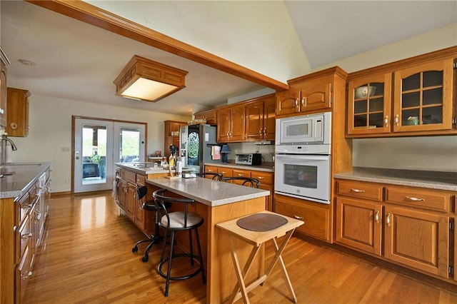 23800 Lucille Ln, Peculiar, MO 64078 - kitchen with white appliances, light wood finished floors, brown cabinetry, and vaulted ceiling