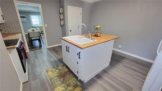 4216 E 67th Ter, Kansas City, MO 64132 - kitchen with electric range, butcher block countertops, dark wood-style flooring, a center island with sink, and white cabinets