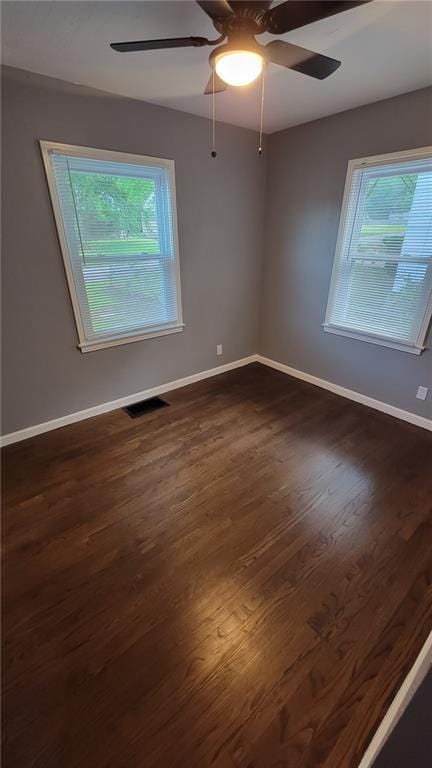 4216 E 67th Ter, Kansas City, MO 64132 - empty room featuring healthy amount of natural light, ceiling fan, and dark wood-style floors